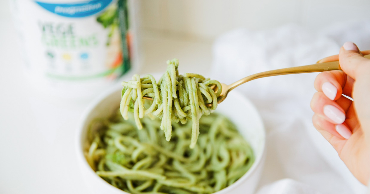 Basil pesto pasta on a white kitchen counter with VegeGreens in the background