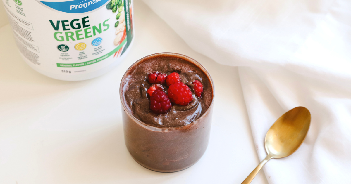chocolate avocado mousse topped with raspberries on a kitchen counter next to VegeGreens