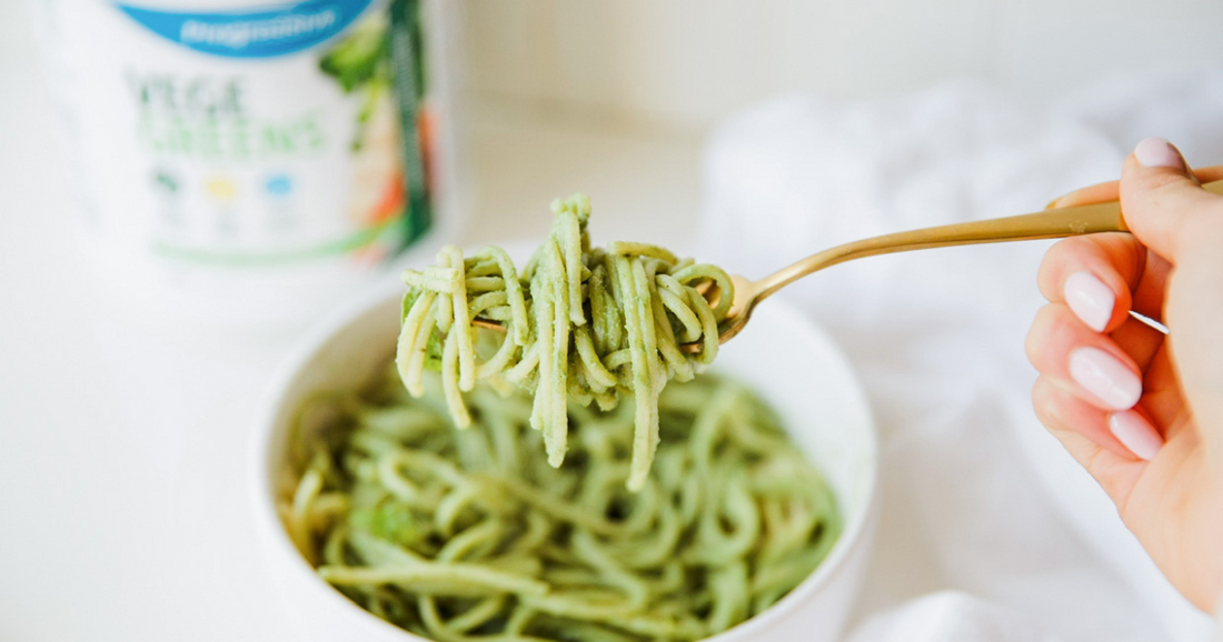 Basil pesto pasta on a white kitchen counter with VegeGreens in the background