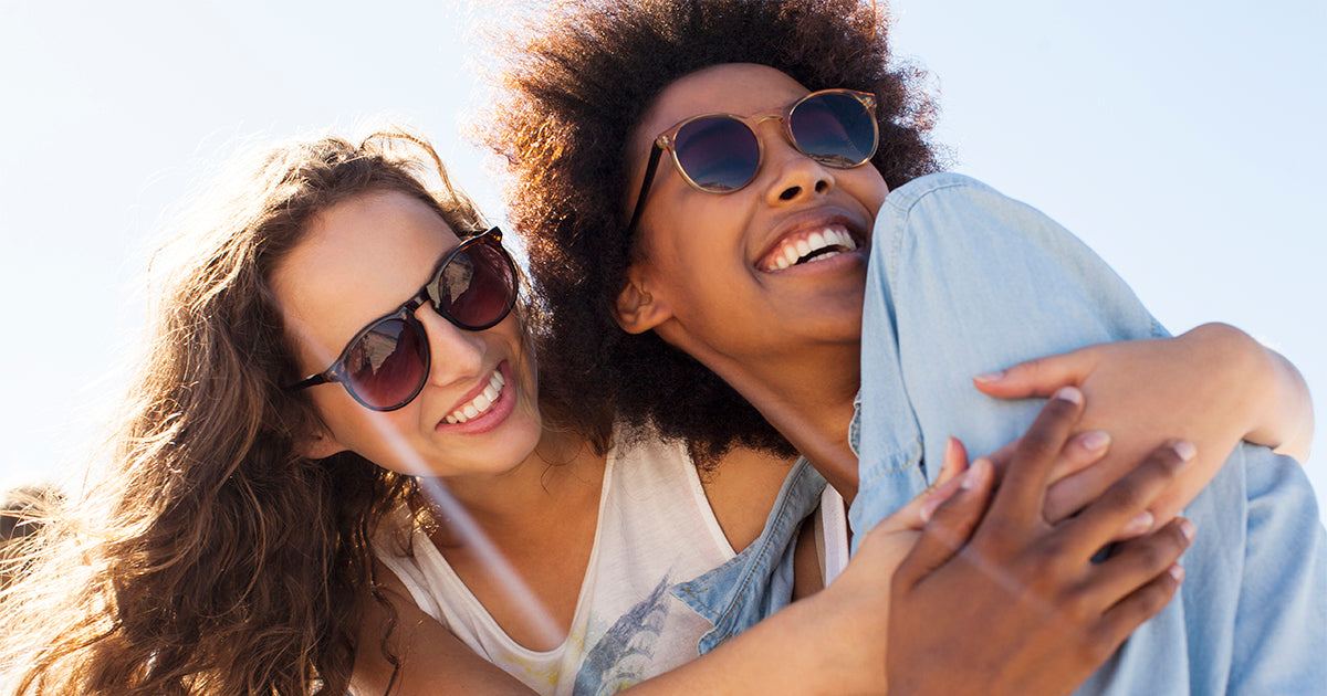 women smiling wearing sunglasses