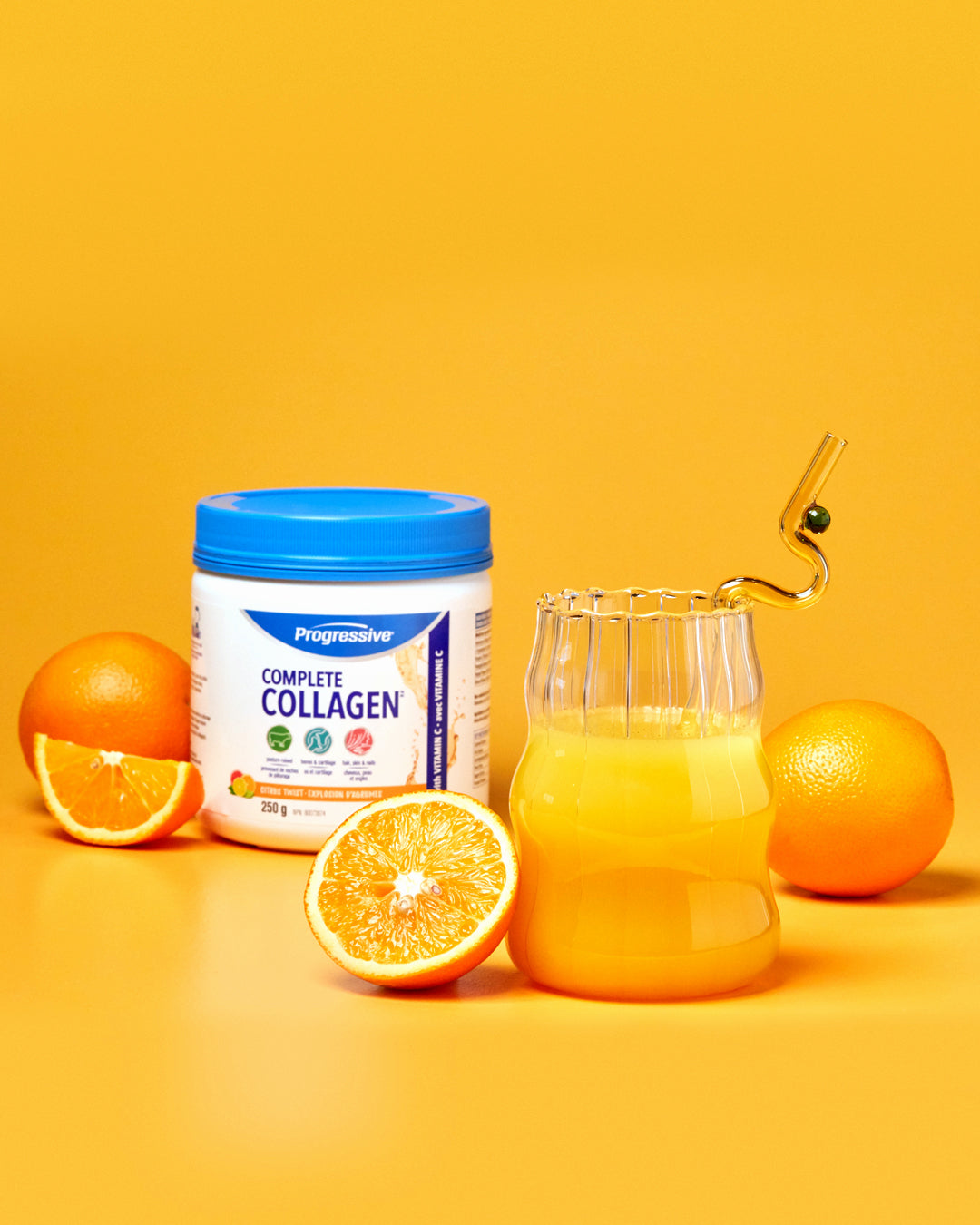 Progressive Complete Collagen Powder on a orange background with orange fruit and juice.